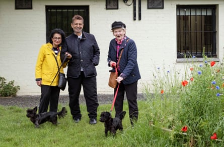 Vera and Shiv Bagga with Sheila Smith-Pryor with two black dogs on grass outside a cafe