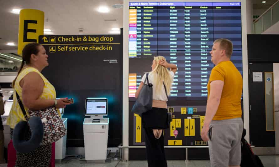 People look at a departures board at Gatwick Airport.