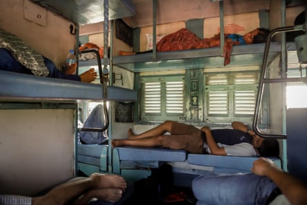 A carriage full of several passengers lying down on train seats turned into beds