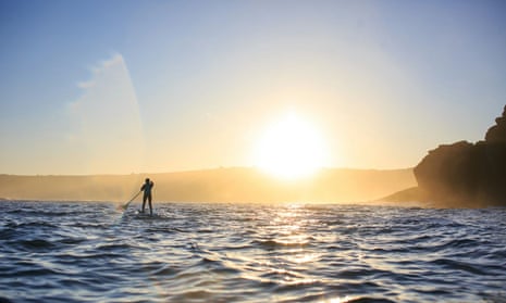 paddleboarder, rocks and sunrise