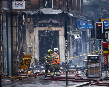 Two firefighters standing outside a burnt-out doorway
