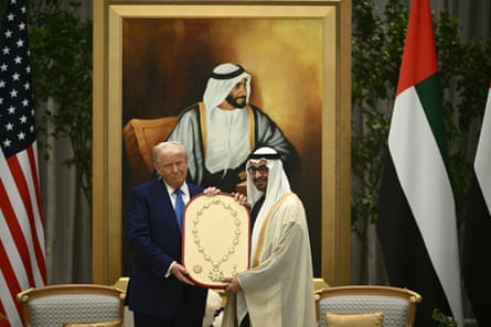 two men stand together holding a golden necklace