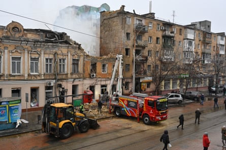 A fire engine in front of a badly damaged and smouldering building