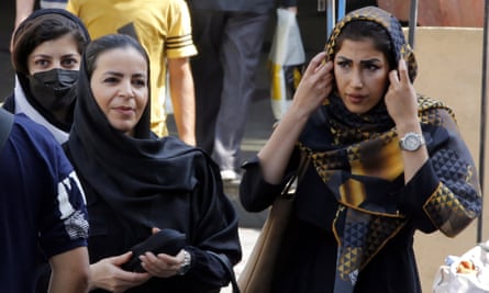 An Iranian woman adjusts a headscarf