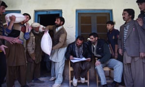 Pakistani earthquake survivors receive supplies at a distributing point in Charun Avir village, some 60km north of Chitral.