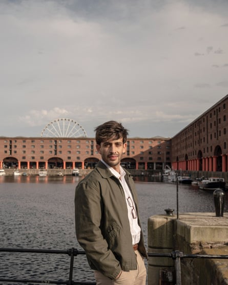 A man in a khaki jacket poses in front of Royal Albert Dock, Liverpool.