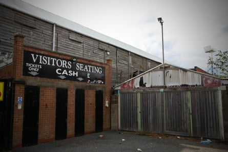 Entrance to old, small local stadium building with brick doorways and a vintage sign reading Visitors Seating, tickets only.