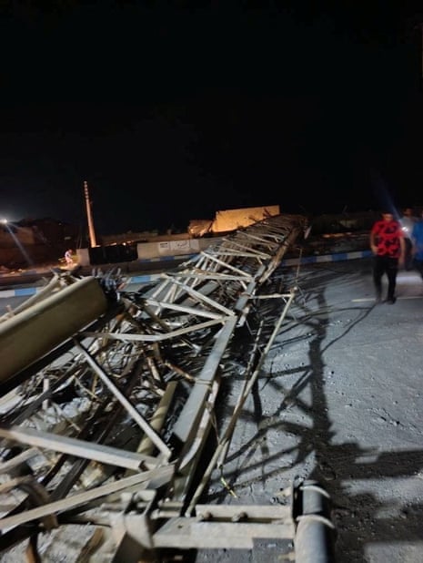 A man walks past a wrecked structure and debris.