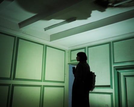 The silhouette of a woman in a green-hued panelled room.