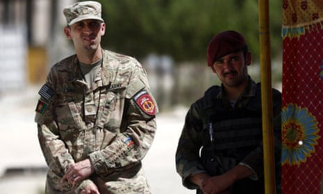A US soldier stands beside an Afghan soldier as they inspect the scene of the suicide bomb in Kabul, Afghanistan.