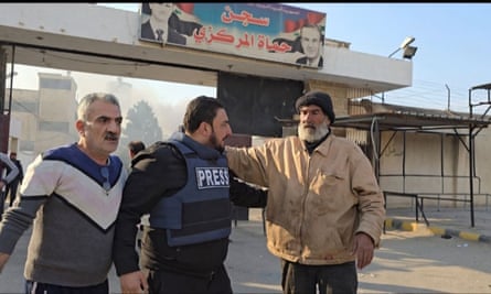 ثلاثة رجال يقفون في الشارع، من بينهم علي حسن العلي ورجل يرتدي سترة الصحافة