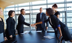 Business people shaking hands across tableLarge group of corporate business people