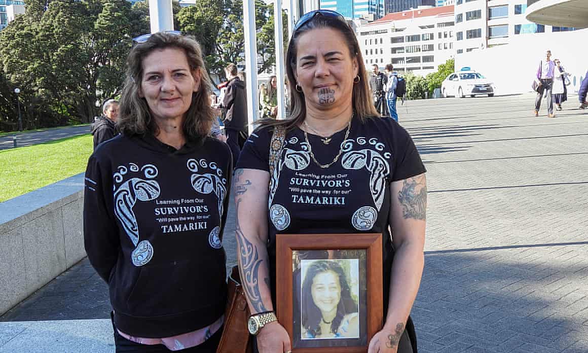 Gina, right, and Tanya Sammons hold a photo of their late sister Alva as they stand for a picture
