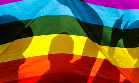 Silhouettes of people against a rainbow flag