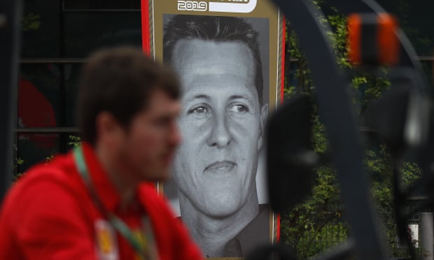 A Ferrari team crew member drives a forklift past a poster of former F1 champion Michael Schumacher.