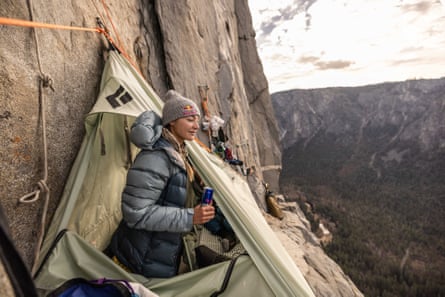 Woman in tent on portaledge looking out at valley thousands of feet below