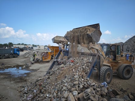 Bulldozer moving piles of rubble and other debris on a concrete crushing site