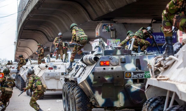 Soldiers jump down from armoured vehicles by a flyover.