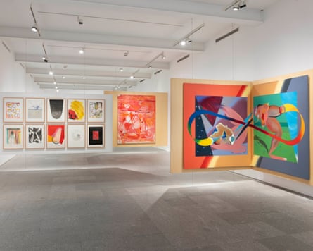 Brightly coloured paintings on display in a large, well-lit room with white walls and grey floor