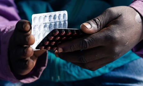 A patient holds two unopened blister packs of tablets