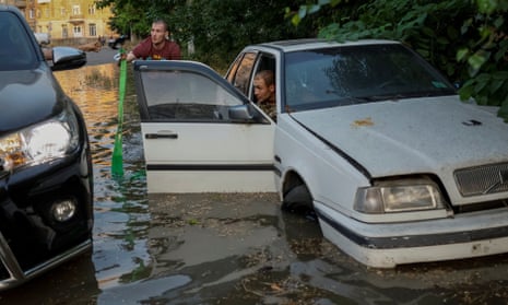 Local residents try to retrieve their car from a flooded street