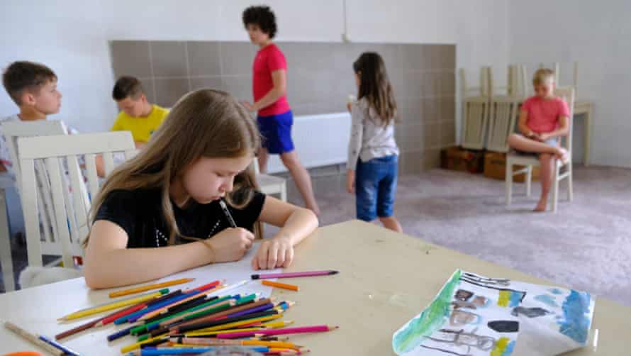 A Ukrainian child paints on paper at a refugee camp’s school in Dnipro.