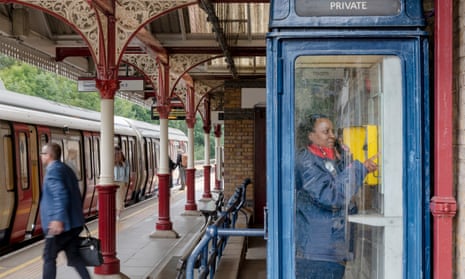 A blue K8 kiosk at Chorleywood station with female member of staff inside