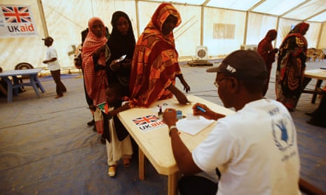 UK aid officials administer a cash assistance project implemented by the World Food Programme at a UN refugee camp in the city of Nyala, in the Sudanese state of South Darfur