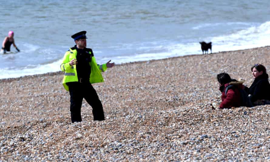 A police officer asks people to leave the beach at Brighton.