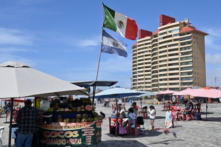 A bright, sunny beach with multiple sun umbrellas and a high-rise building in the background.