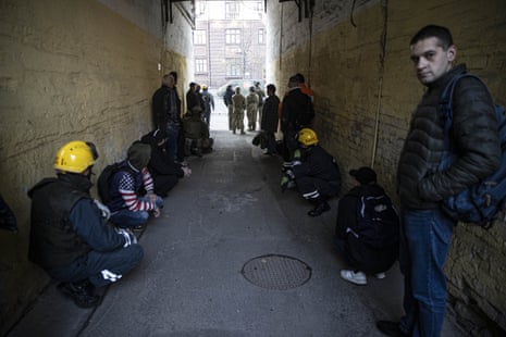 Firefighters and civilians wait in a safe area due to a threat of new attacks.