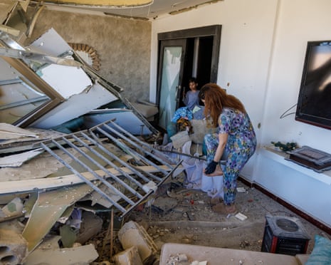 A woman checks her foot as she cleans her apartment in a building damaged by an Israeli strike in Tyre, southern Lebanon, amid the ceasefire