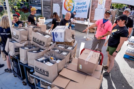 People in shorts and T-shirts move dozens of boxes outside.