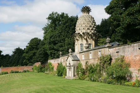 A folly with a pineapple tower, with a walled garden in front and trees behind