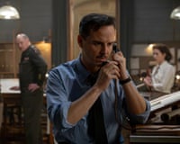 Captain James Stagg, played by Andrew Scott, speaks on a telephone in a busy office