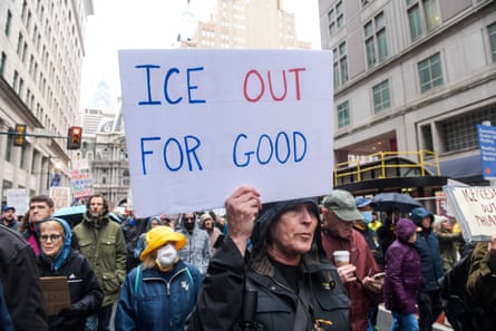 Woman in a crowd holds sign that says "Ice out for good."