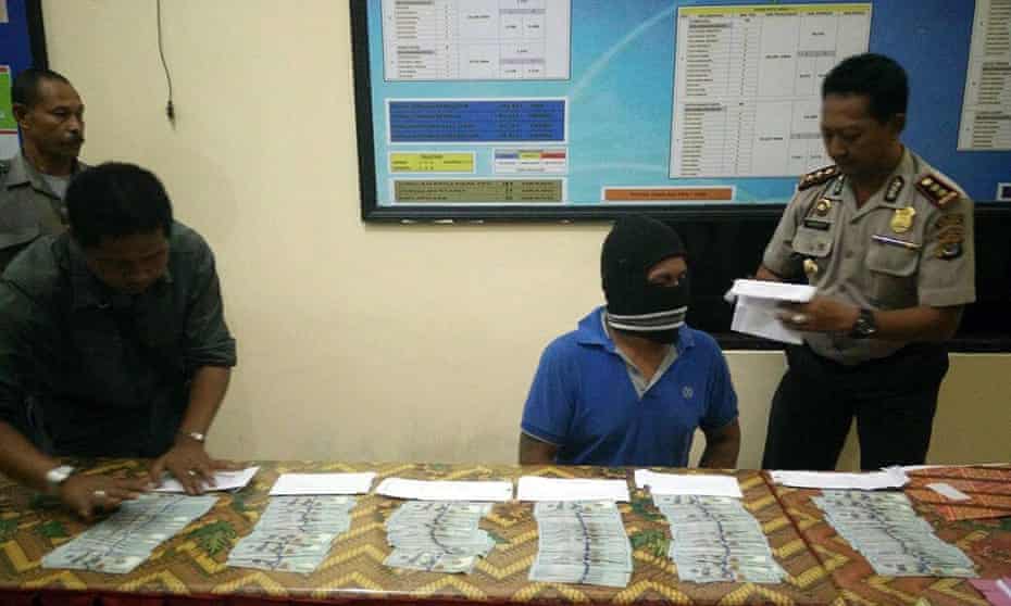 A handout picture released by Indonesian Police on 17 June 2015 shows an Indonesian crew member (C) of an alleged people-smuggling boat and a table of USD notes allegedly given to the crew of the boat by an Australian official to bring illegal migrants back to Indonesia.