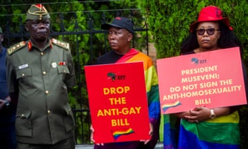 people hold signs that read 'drop the anti-gay bill' and 'president Museveni: do not sign the anti-homosexuality bill'