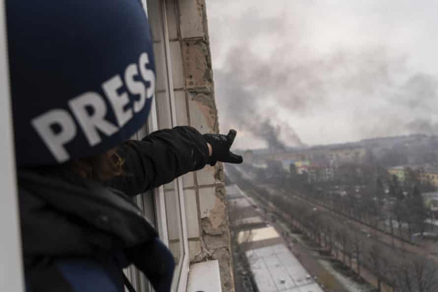 Evgeniy Maloletka points at the smoke rising after a strike on a maternity hospital in Mariupol on 9 March.