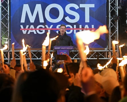 Supporters hold torches as Péter Magyar speaks at a campaign rally