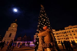 A couple embrace next to a Christmas tree in front of St Sophia's Cathedral during a New Year’s Eve celebration before a curfew in Kyiv