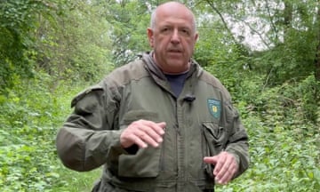 Heinrich Koch wearing a green army-style jacket standing in a wooded area