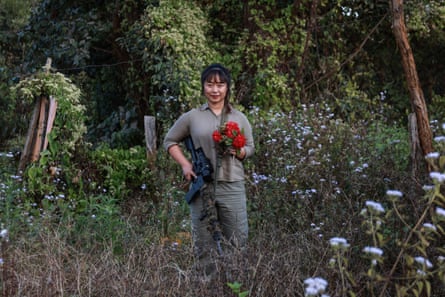 A woman holding a bunch of red flowers in a field of blue flowers