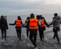 A child is carried as people walk into the sea to board a dinghy in Gravelines, France.