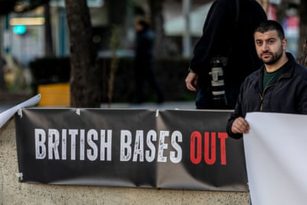A man stands next to a sign that reads ‘British bases out’