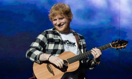Ed Sheeran playing his trademark small guitar on stage