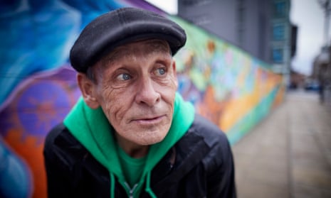 Danny Collins, who was homeless, stands next to graffiti art painted by homeless people in Manchester.