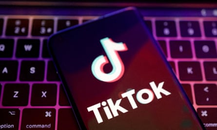 TikTok app logo on a phone near a laptop keyboard
