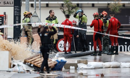 Police and firefighters standing while water is pumped out in Aldaia, Valencia.