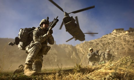 US soldiers take position as a helicopter flies overhead in Khost province, Afghanistan
